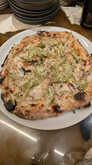 Japan Umami pizza with dried shiitake mushroom cream sauce, mozzarella, pecorino, mackerel, bonito flakes, konbu, green onion, sesame, and soy sauce. So very unique flavours.